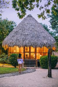 a woman walking in front of a hut at Turtle Inn in Placencia Village