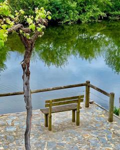 una panchina di legno seduta accanto a un corpo d'acqua di Casa do Rio Alva ad Arganil