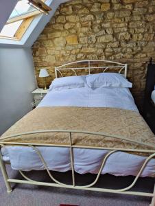 a bed in a room with a stone wall at The Lampet Arms in Banbury
