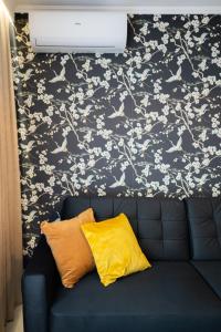 un sofá azul con una almohada amarilla contra una pared floral en Apartament 55m2 - Darmowy Garaż - Klimatyzacja - Centrum - 24na7, en Wroclaw