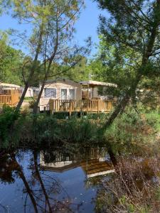 dom z tarasem i stawem w obiekcie Envie d un break de paysages sauvages et de nature ce mobile home neuf tout confort climatise idealement situe au bord de l eau dans un camping 4 etoiles vous attend pour un week end quelques jours ou des vacances en famille w mieście Cap-Ferret