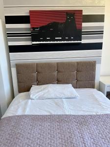 a bed with a picture of a black cat on the wall at Golden Triangle Budget Rooms in Norwich