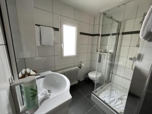 a bathroom with a sink and a shower and a toilet at City Hotel in Schopfheim