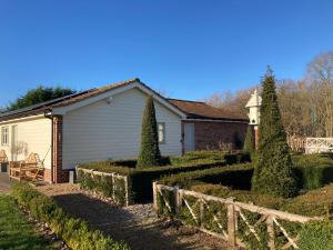 The Oaks Stable cottage في Haughley: منزل به حديقة بها أشجار وسياج
