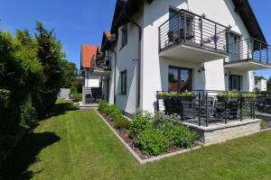 a white house with a balcony and a yard at Piaskowy 2 in Jantar