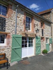 un antiguo edificio de piedra con puertas y ventanas verdes en La grenouille amoureuse, en Menat