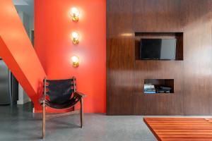 una silla en una habitación con una pared de color naranja en Unhotel - Aluguel de Apartamento em Ipanema ao lado da praia, en Río de Janeiro