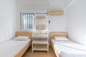 twee bedden in een kamer met een raam bij Apartment 1km from Acropolis Filoppapou Hill in Athene