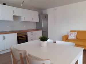 een keuken met een witte tafel en stoelen en een bank bij Rural Confort Cataluña-Sur in Campredó