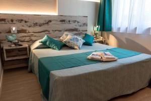a bedroom with a large bed with green sheets and blue pillows at Hotel Acquamarina in Portoferraio