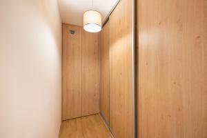 korytarz z drewnianymi drzwiami i światłem w obiekcie Saska Kępa Bright Apartament w Warszawie
