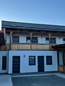 Casa blanca con puertas negras y balcón en Casa de lângă pădure, en Sighetu Marmaţiei