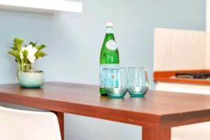 a green bottle and two glasses on a wooden table at Kas di Amigu in Kralendijk