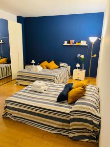 two beds in a room with blue walls and yellow pillows at Chiara Guest House - Nuova Metro blu in Milan