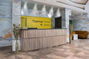 a hotel lobby with a yellow sign and a counter at Thermal Hotel Garden in Hajdúszoboszló