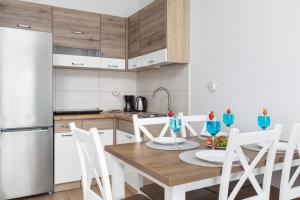 a kitchen with a wooden table with chairs and a refrigerator at Nad Zalewem - Familijny Apartament z Widokiem na Zatokę by Renters in Dziwnówek