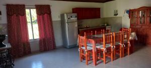 een keuken met een tafel en stoelen en een koelkast bij Cabaña Aguara in Colonia Carlos Pellegrini