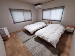 Takeshima - Vacation STAY 61918v في ناروتو: سريرين في غرفة بها نافذتين وسجادة