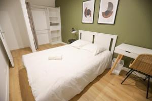- une chambre avec un grand lit blanc et un bureau dans l'établissement Appart'Hôtel Le Bright Evry- 4 Chambres Design, à Évry-les-Châteaux