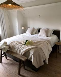 a bedroom with a large white bed with a bench at De Bijenkorf in Damme