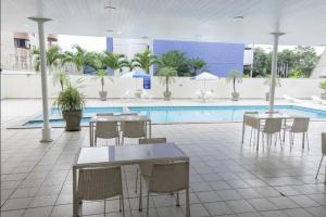 a patio with tables and chairs and a swimming pool at Flat no Executive Arrey Hotel in Teresina
