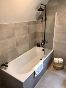 een badkamer met een wit bad en een douche bij De Bijenkorf in Damme