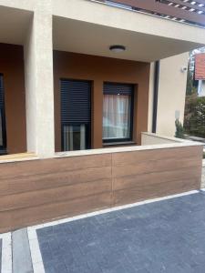a house with a wooden bench in front of two windows at Gomax apartman 4 in Zlatibor