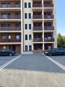 dwa samochody zaparkowane na parkingu przed budynkiem w obiekcie Gomax apartman 4 w mieście Zlatibor