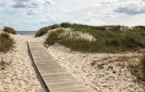 un sentiero in legno su una spiaggia sabbiosa vicino all'oceano di Beautiful Home In Hassl With Wifi a Hasslö