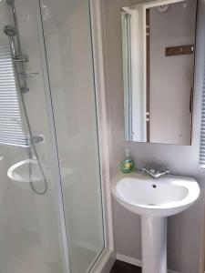 a bathroom with a sink and a shower with a mirror at Lake District 2021 Deluxe Static Caravan on Haven Lakeland in Flookburgh