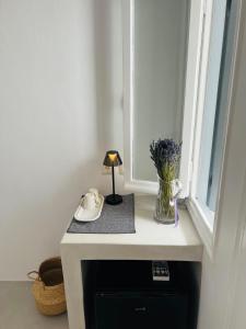 a window sill with a phone and a lamp on a table at Camara Homes in Andros