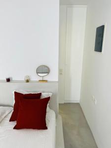 a bedroom with a white bed with a red pillow at Camara Homes in Andros