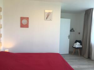 1 dormitorio con cama roja y pared blanca en Hôtel Restaurant - Le Vieux Pigeonnier en Loubressac