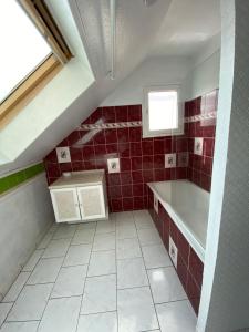 a red tiled bathroom with a sink and a window at Maeva in Pontorson