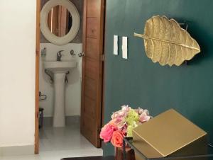 uma casa de banho com um lavatório e uma mesa com flores em Oasis Palma Real santiago, Republica Dominicana em Santiago de los Caballeros