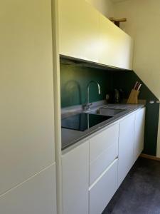 a kitchen with white cabinets and a sink at M&M Apartment in Perca