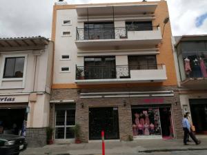 a man walks past a building with a balcony at Hostal NIZZA in Cuenca