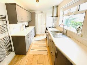 a kitchen with white counters and a sink and a window at Calla's place in Derry Londonderry