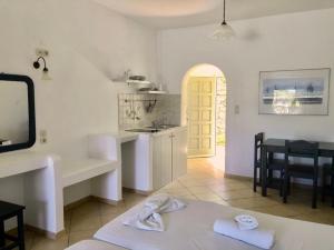 a white kitchen with a sink and a table at Agios Pavlos Studios in Aegiali