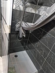 eine Dusche im Bad mit schwarzen Fliesen in der Unterkunft appartement avec balcon in Hargarten-aux-Mines