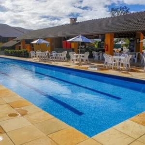 a swimming pool with chairs and tables and umbrellas at Flat 419 - Winterville-Gravatá in Gravatá