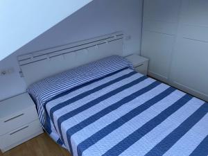 een kleine slaapkamer met een blauw en wit gestreept bed bij VIVIENDA BOCA DO RIO- Carnota in Carnota
