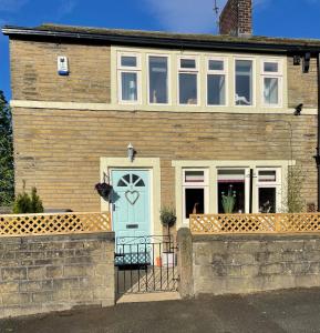 een bakstenen huis met een blauwe deur en ramen bij Cute and cosy 2 bed cottage in Honley
