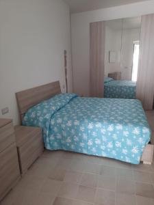 Dormitorio con cama con edredón azul y espejo en Appartamento su palazzina storica in centro a Sant'Antioco, en SantʼAntìoco