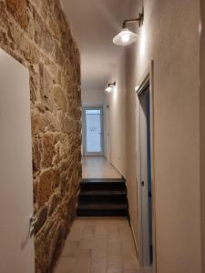 um corredor com uma parede de pedra e uma escada em Appartamento su palazzina storica in centro a Sant'Antioco em SantʼAntìoco