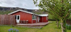 uma cabina vermelha com um deque de madeira num quintal em Ægisholt privete house with hot tub em Patreksfjörður