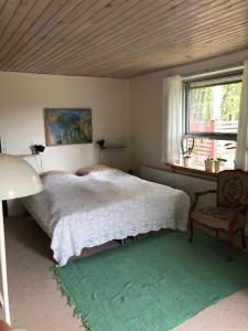 a bedroom with a bed and a chair and a window at Maren's apartment on Randbøl Heath in Randbøl