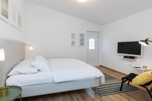 a white bedroom with a bed and a flat screen tv at Villa Feral Apartments in Crikvenica