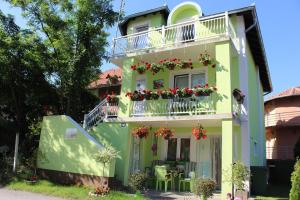 a green house with a balcony with flowers on it at Apartmani Cirkov in Veliko Gradište
