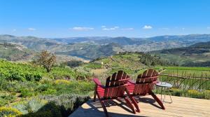 two chairs sitting on a deck with a view of the mountains at Casa de Pena d'Águia - Douro Encantado in Provesende